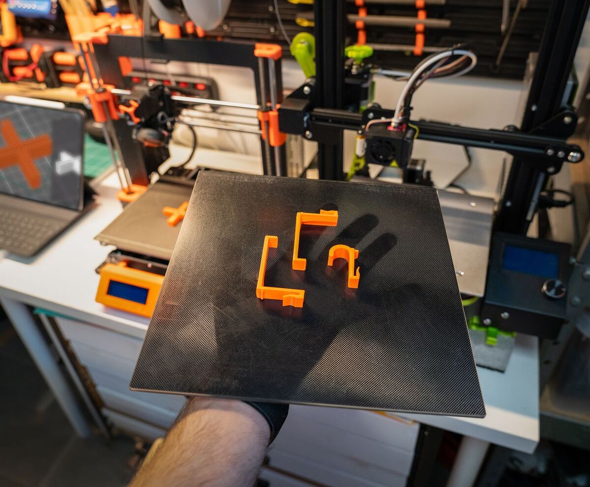 Hand flexing a build plate to release orange printed parts